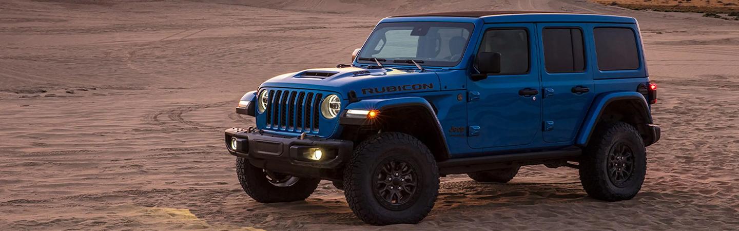 Side view of a blue 2021 Jeep Wrangler Rubicon parked in the desert.