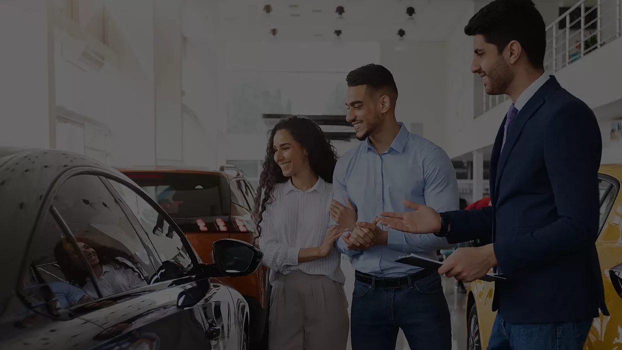 salesman showing husband and wife a vehicle