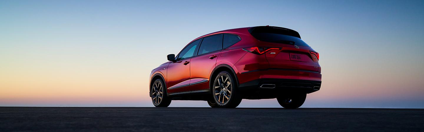 Side profile of a red Acura MDX on the horizon