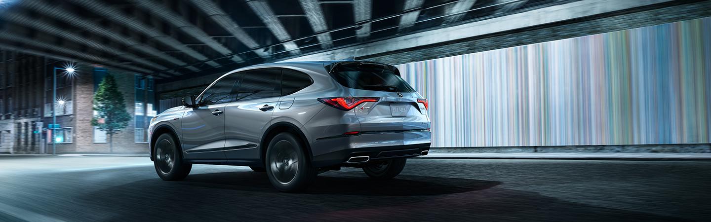 Side profile of a silver Acura MDX driving through a city tunnel