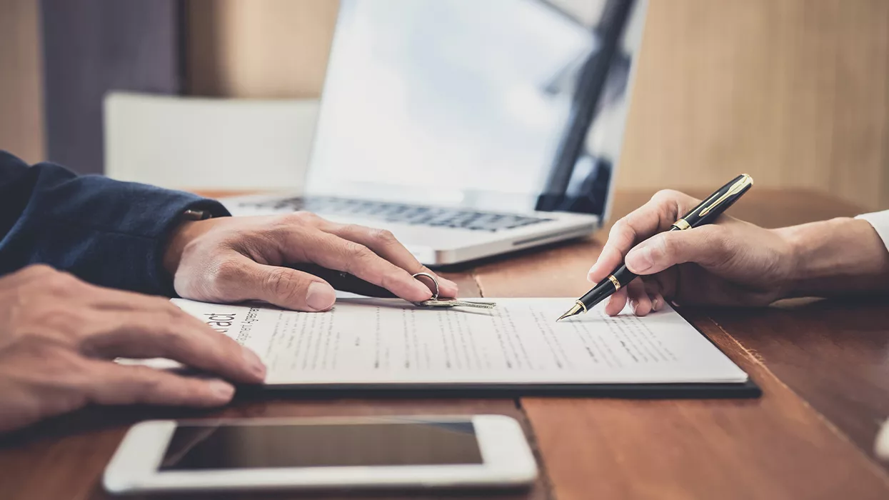 Someone signing a document with another person giving them keys