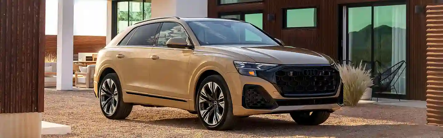Front view of a parked tan 2025 Audi Q8 at a house