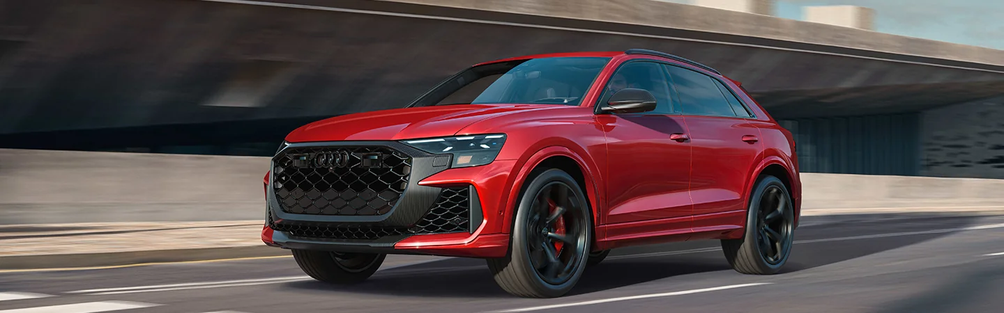 Front side view of a red 2025 Audi Q8 driving on a highway 