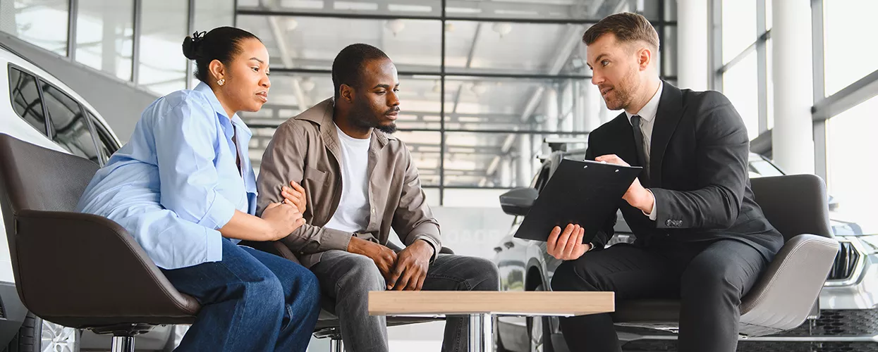 Car salesman talking to a couple about a new car