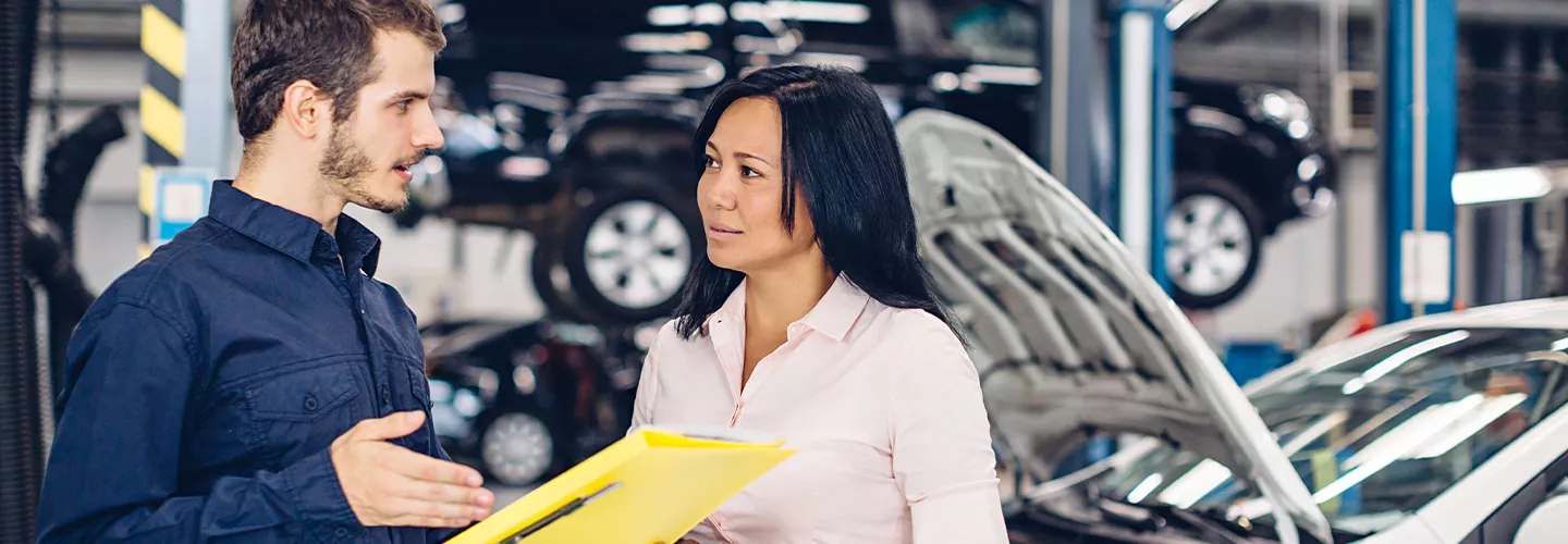Service mehcanic talking to a customer while holding a clipboard