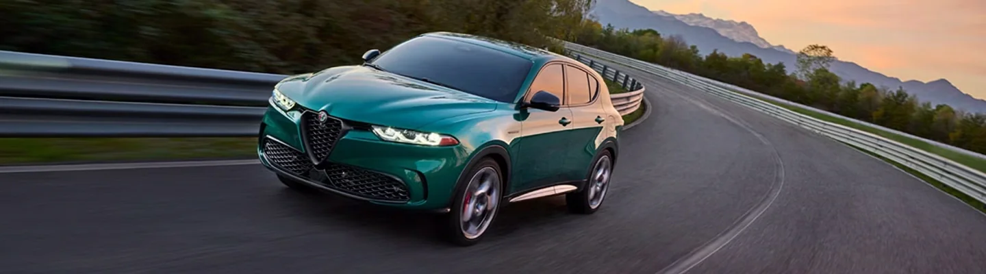 Front view of a green Alfa Romeo Tonale driving on a curvy road