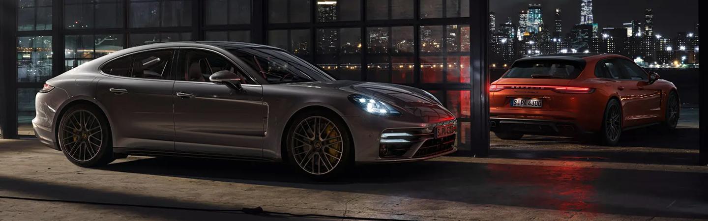 A 2021 Porsche Panamera parked next to a red car by the harbor