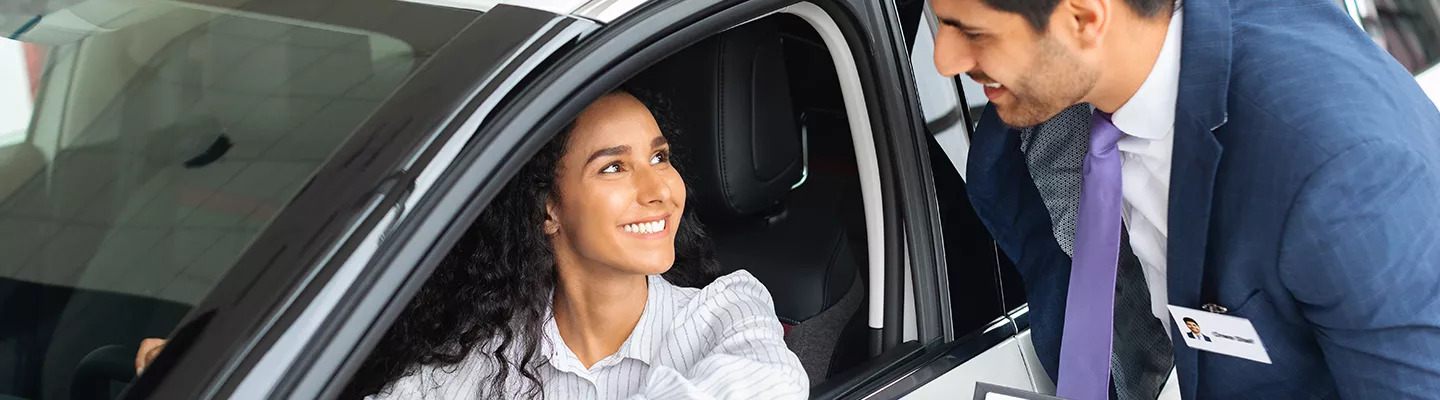 Women sitting in a car talking to a car salesman