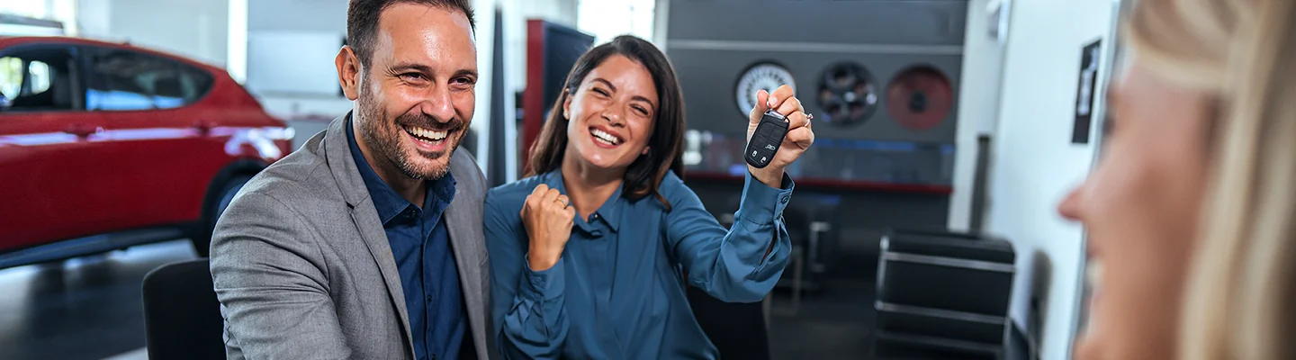a couple smiling with one holding keys to a car