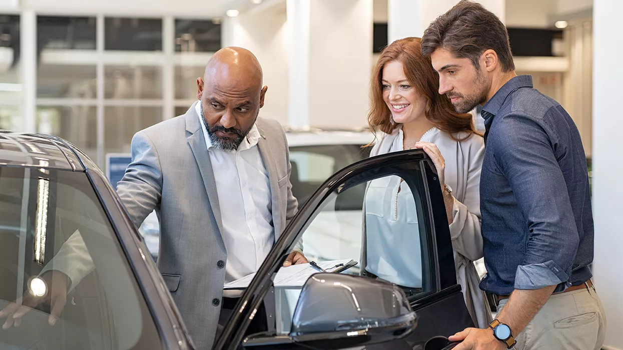 A couple looking at a car with a car salesman