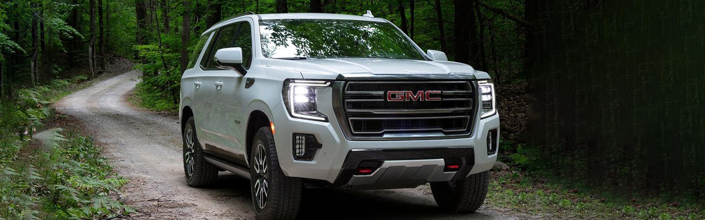 White 2022 GMC Yukon driving in the woods
