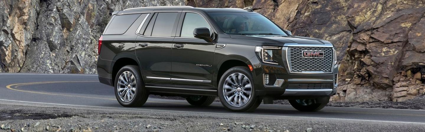 A 2022 GMC Yukon driving on the road next to large rocks