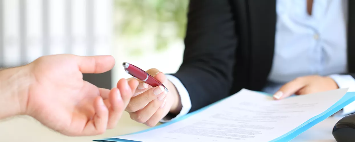 Woman handing a pen to a man with a document in her hand