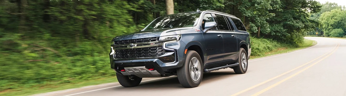 A Chevrolet Tahoe driving on a road by a forest
