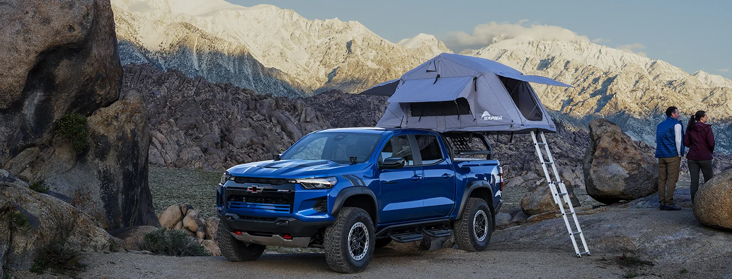 Parked blue 2025 Chevrolet Colorado with a tent on top camping