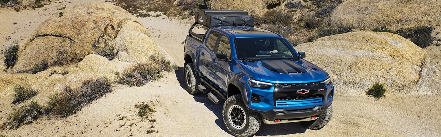 Front view of a blue 2025 Chevrolet Colorado driving on rocks