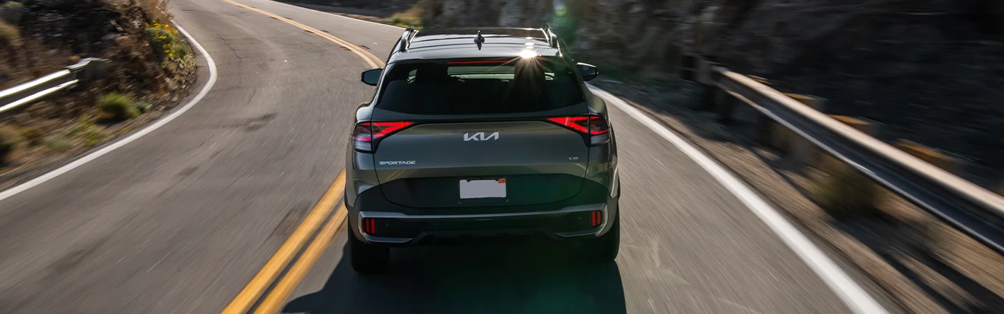 Back view of a green 2025 Kia Sportage driving on the raod
