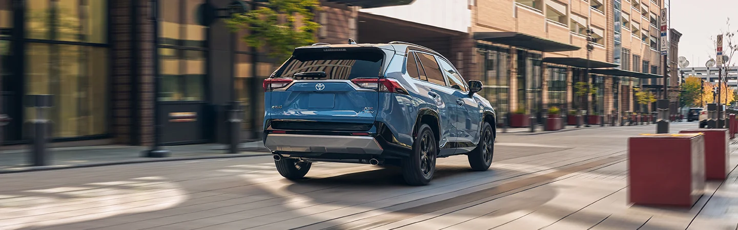 Back view of a blue 2025 Toyota RAV4 driving in the city