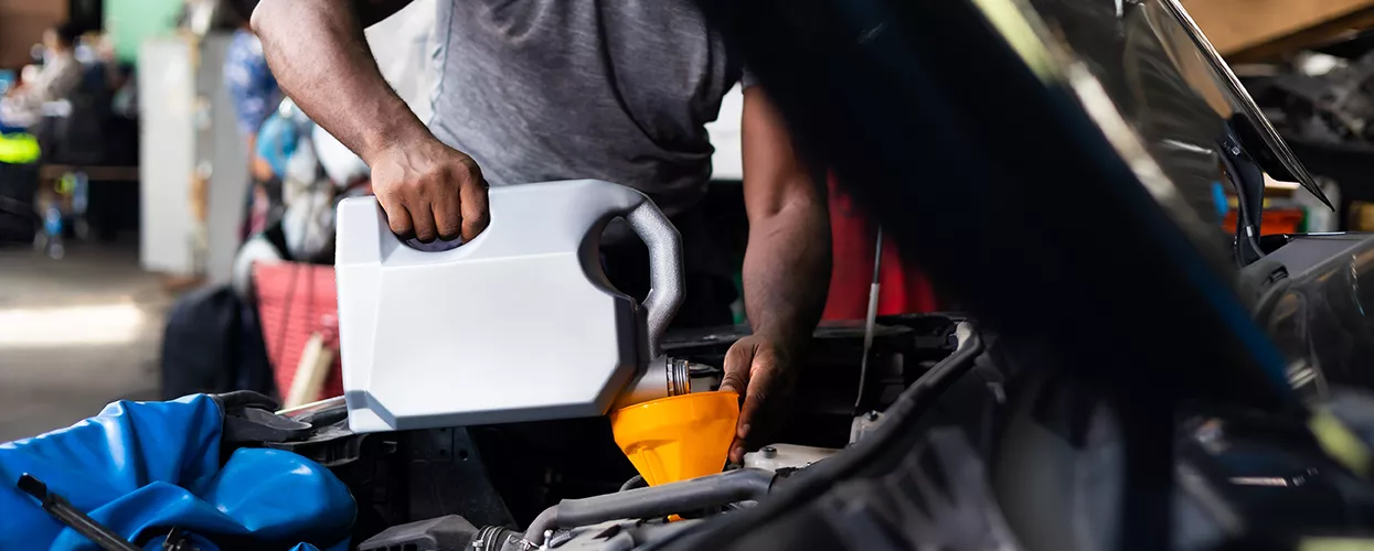 Service mechanic pouring oil into a vehicle