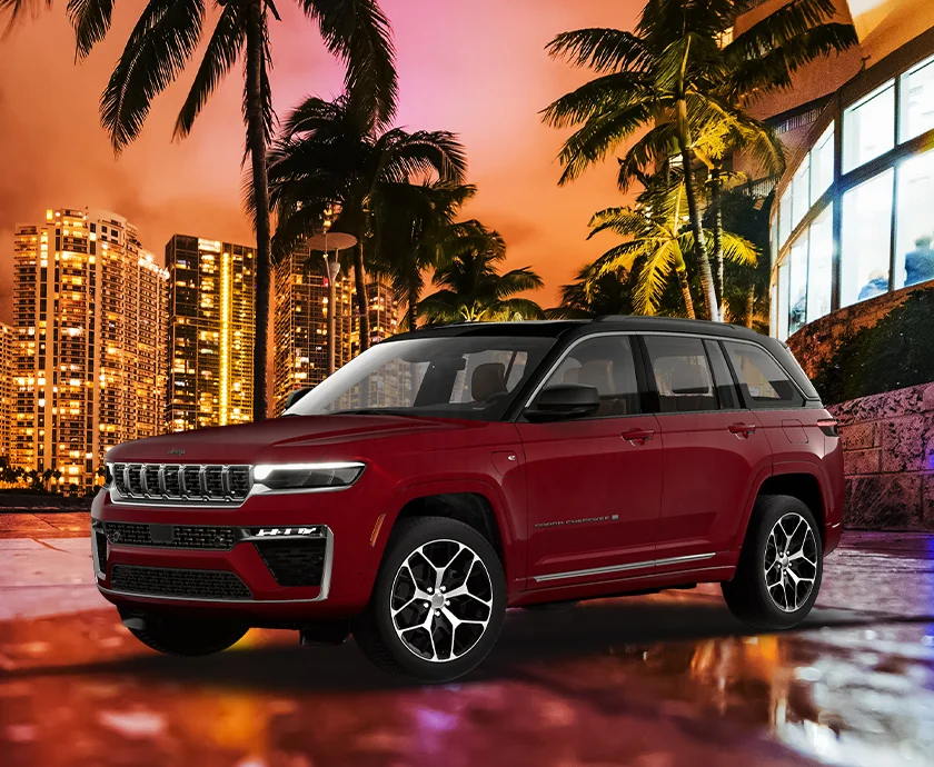 Front side view of a 2026 Jeep Grand Cherokee parked with a city in the background