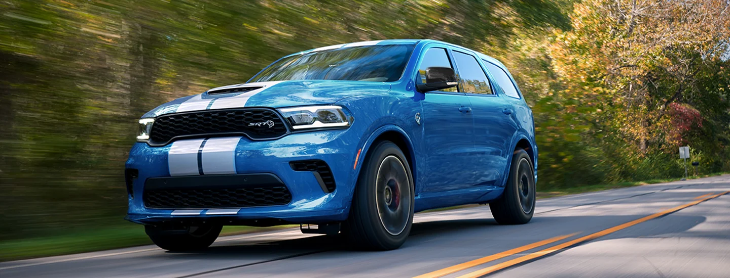 A blue 2025 Dodge Durango with a raceing strip driving on the road