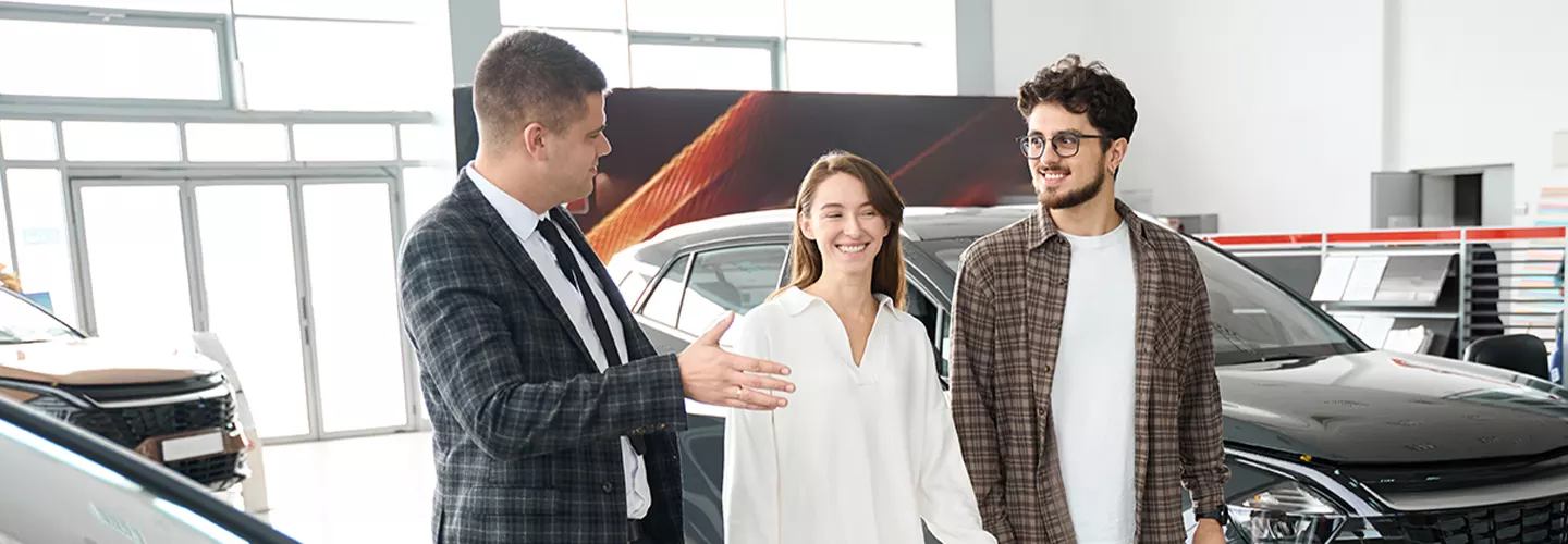 salesman showing man and woman vehicles in the showroom