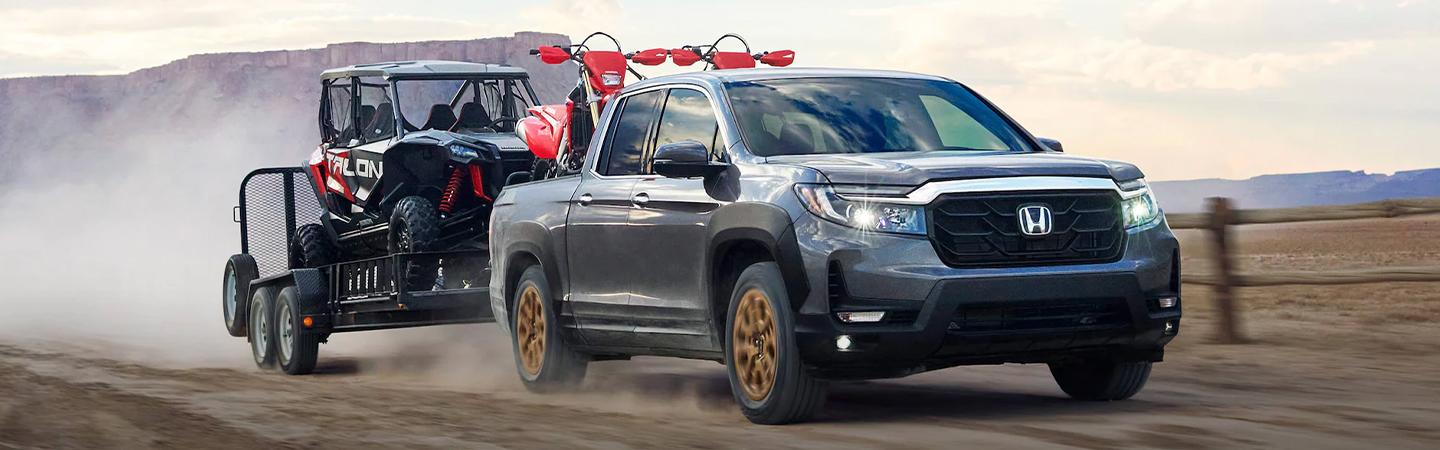 2022 Honda Ridgeline towing 4 wheel ATV on dirt road