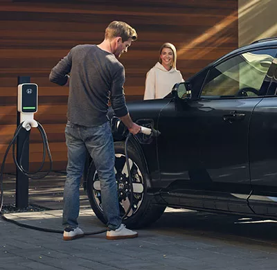 Man charging Honda Prologue electric SUV at home charging station in driveway