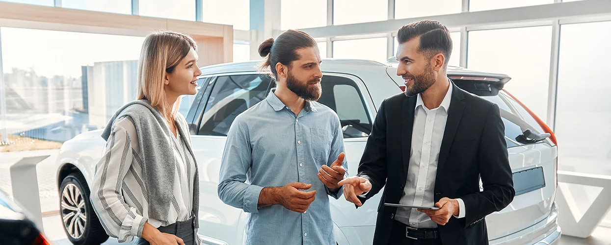 couple discussing SUV purchase in the showroom with car salesperson