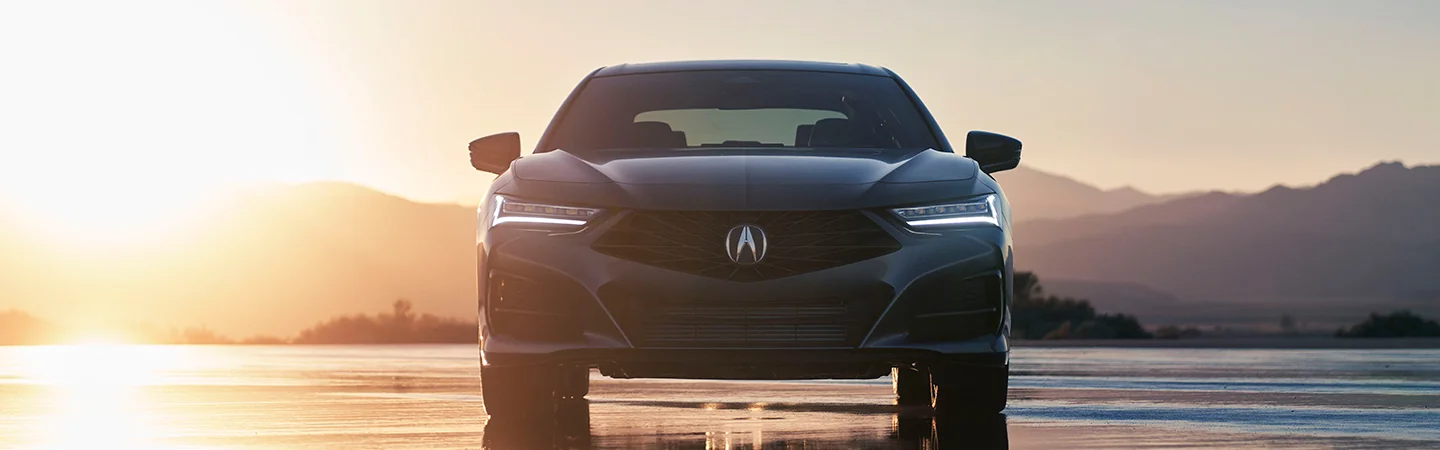 2025 Acura TLX gery car reflecting golden sunset with wet pavement with front view