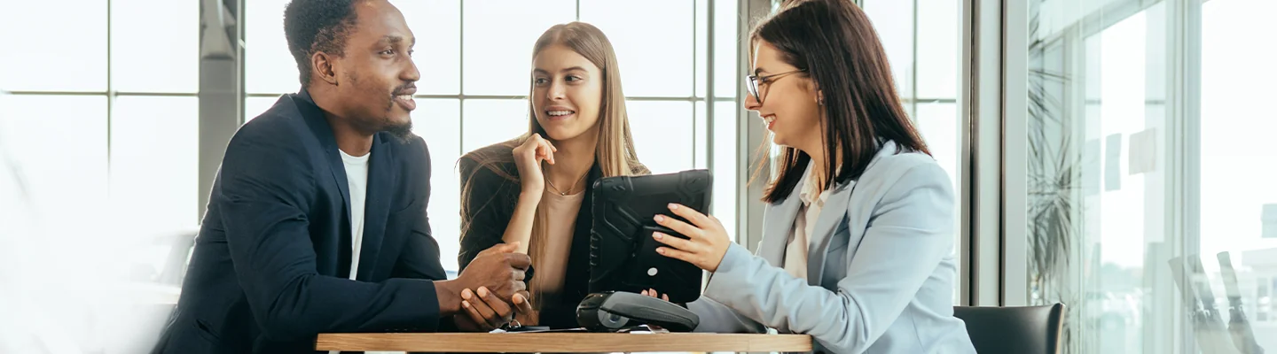 couple speking with a person showing details from a tablet pc she is holding