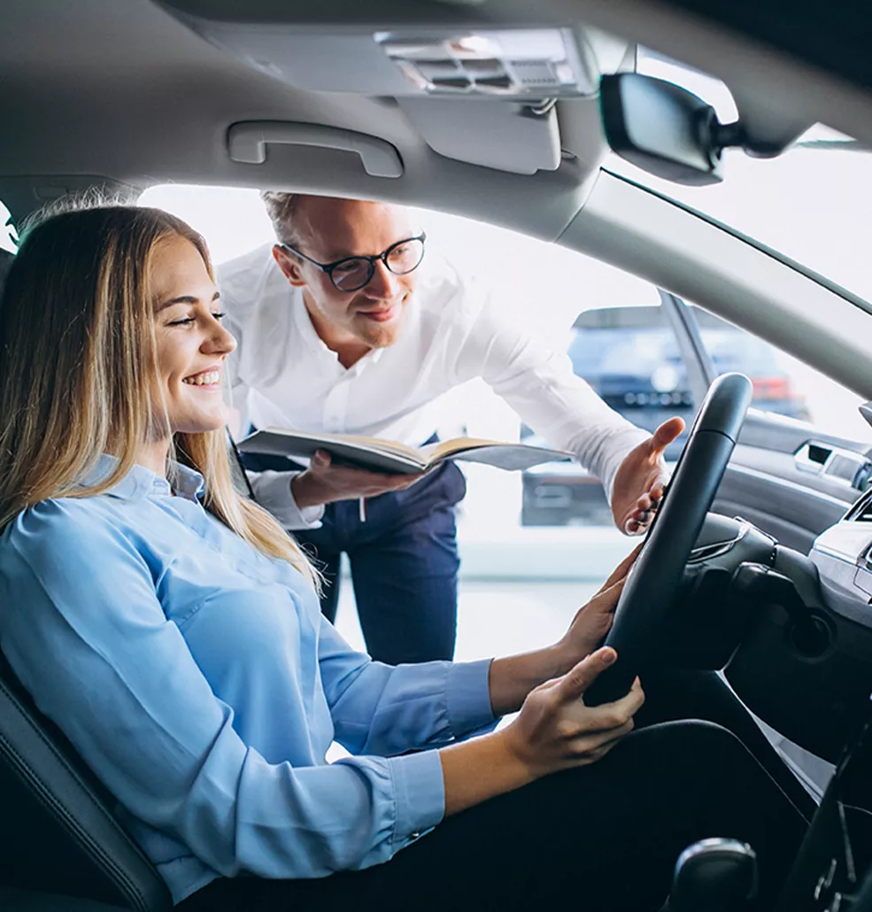 Woman sitting in a new car with a car salesman standing outside
