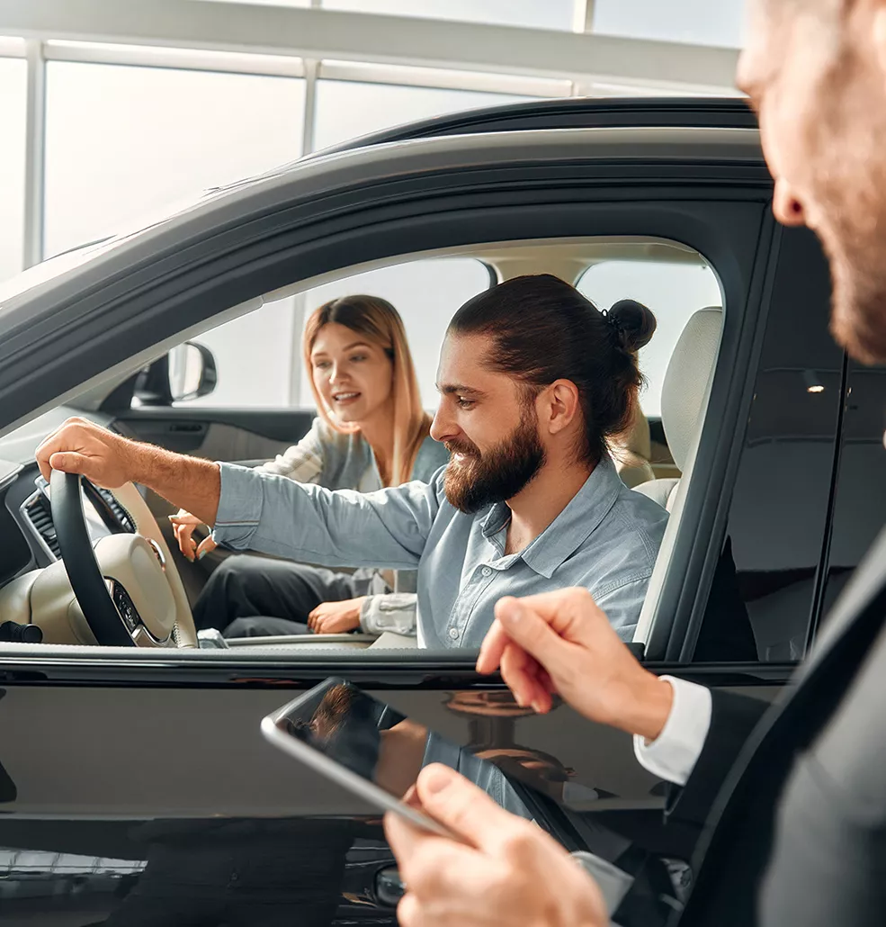 Couple sitting in a new car at a car dealership