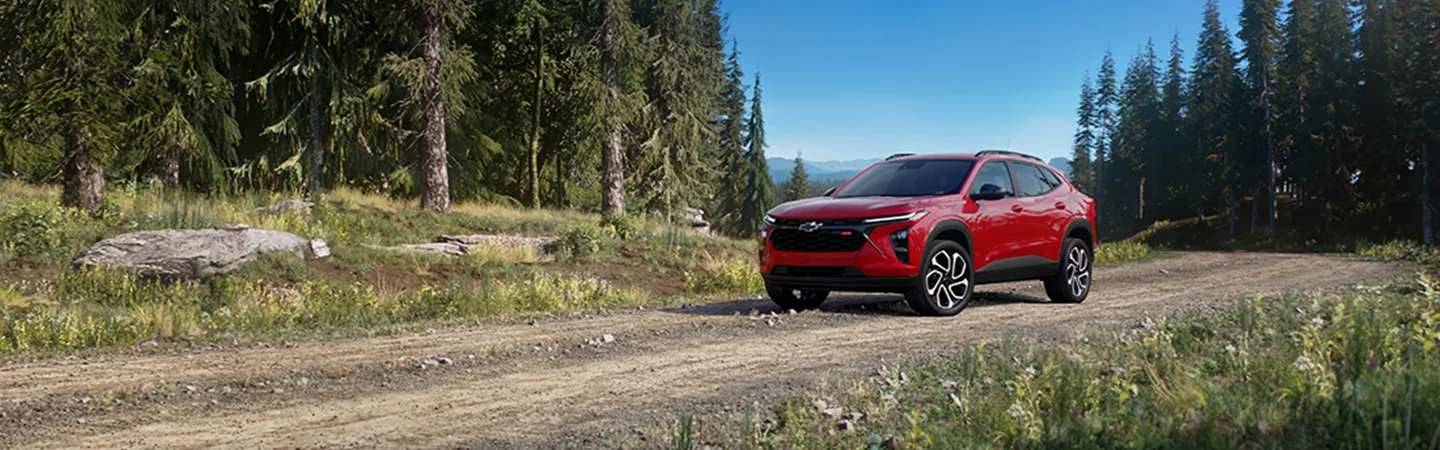 Red 2025 Chevrolet Trax driving though the woods