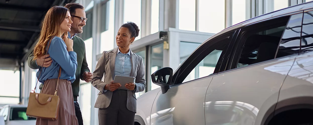 A car saleswoman showing a new car to a couple