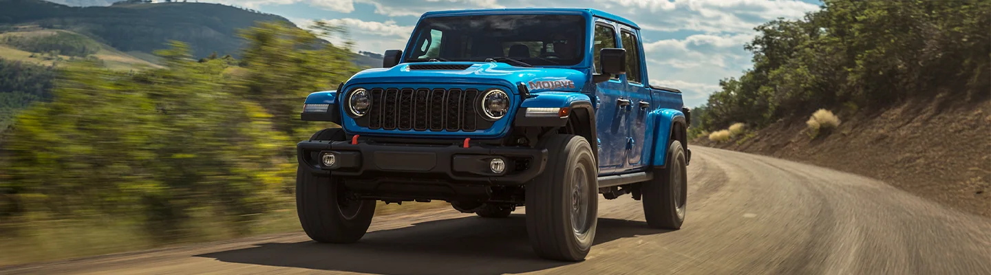 Blue Jeep Gladiator driving in the wilderness