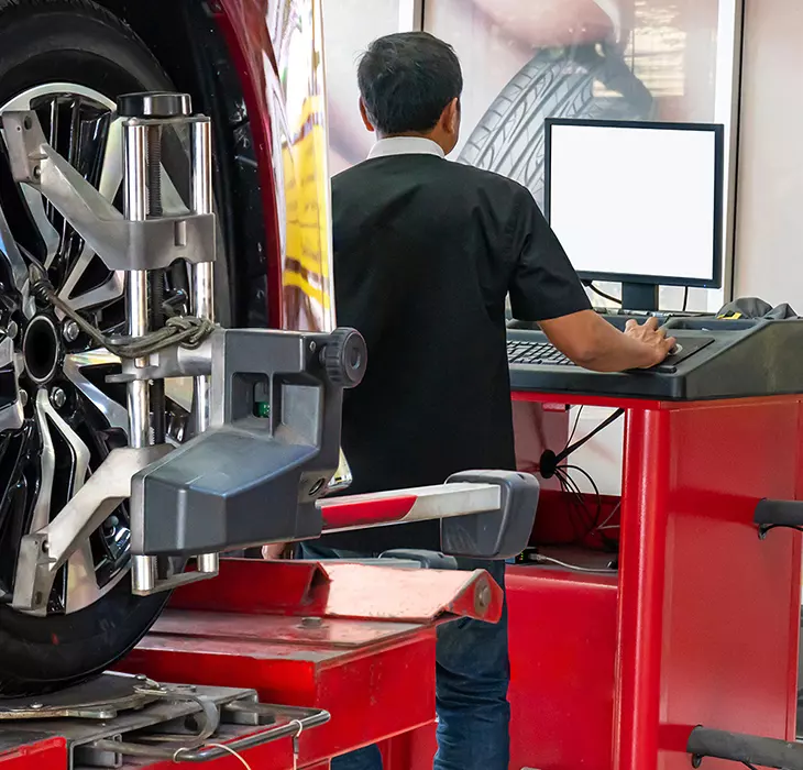 mechanic in the shop room running a diagnosis of a vehicle on the computer
