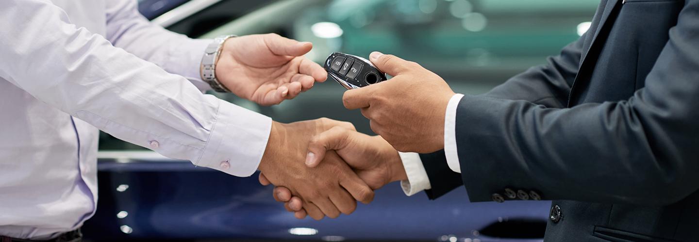 A dealership employee and customer exchanging car keys
