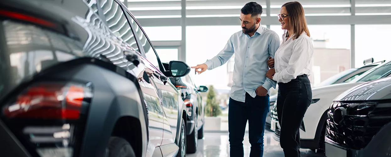 A couple looking at a new vehicle at a car dealership