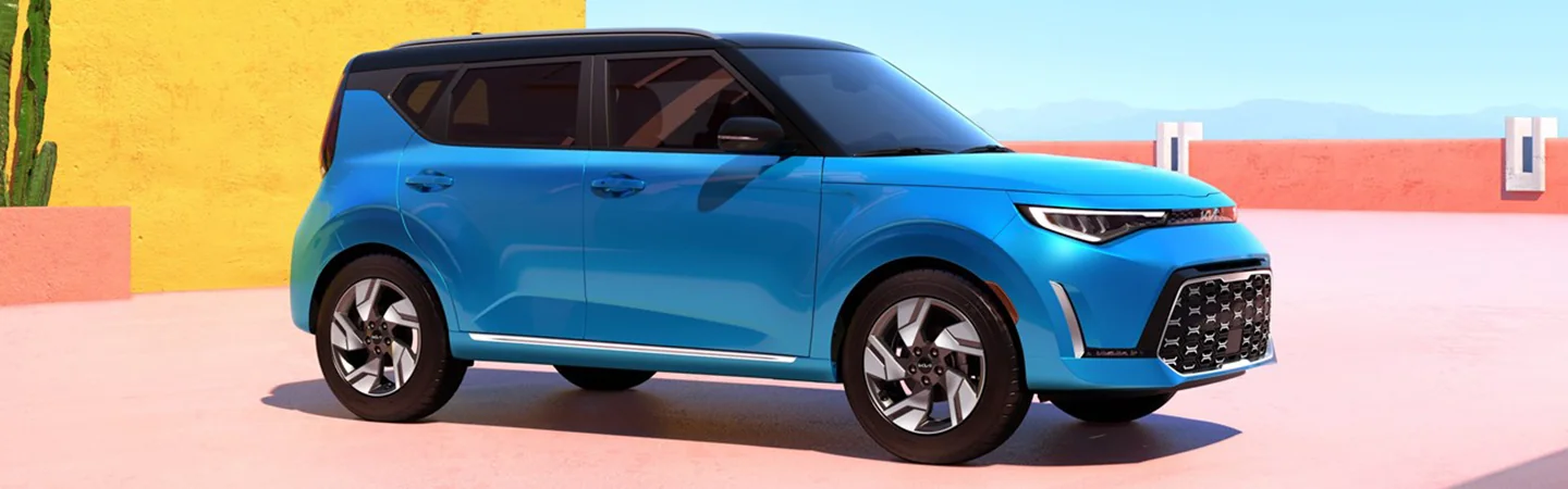 Side view of a parked blue 2025 Kia Soul next to a multi-color house