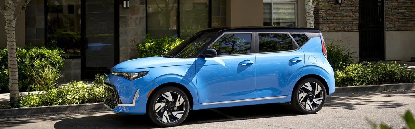 Side view of a parked blue 2025 Kia Soul next to a store front