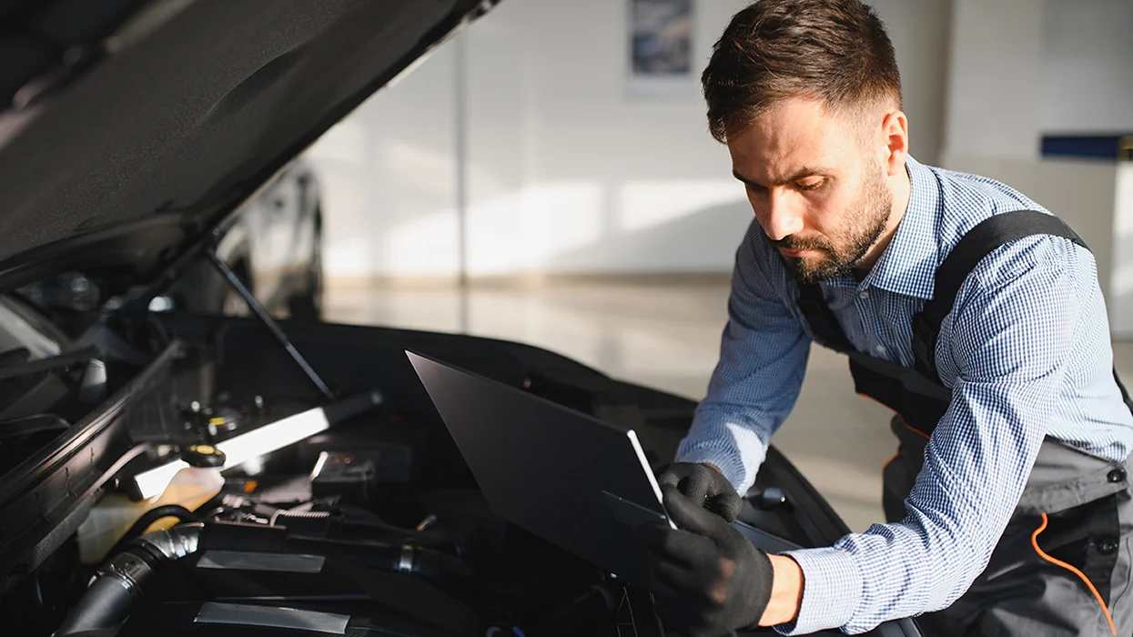 car mehanic working on car testing with laptop