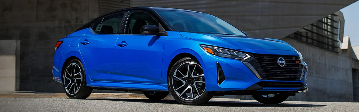 Side view of a parked blue 2024 Nissan Sentra in a driveway