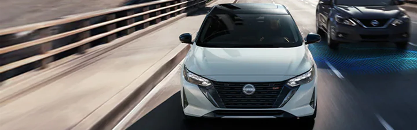 Front view of a white 2024 Nissan Sentra driving on a road