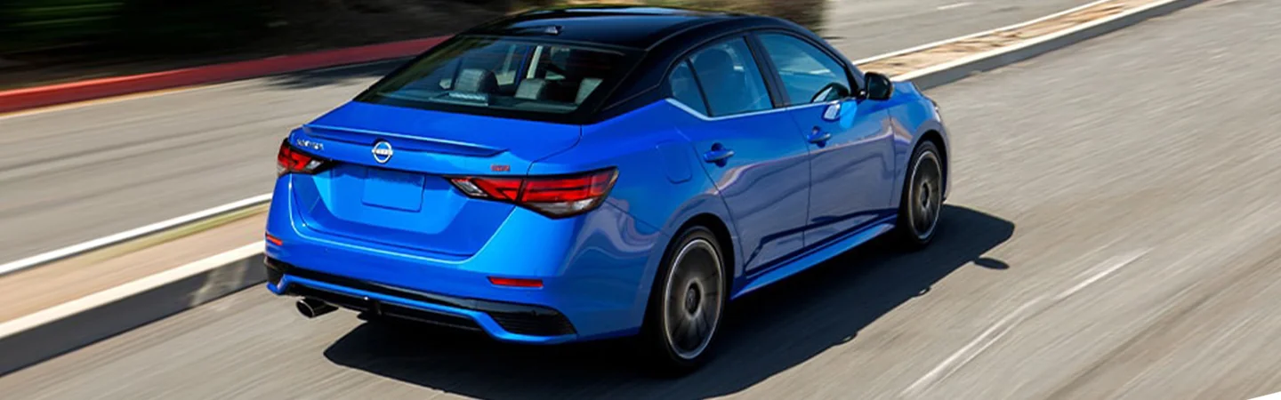 Back side view of a blue 2024 Nissan Sentra driving on a road