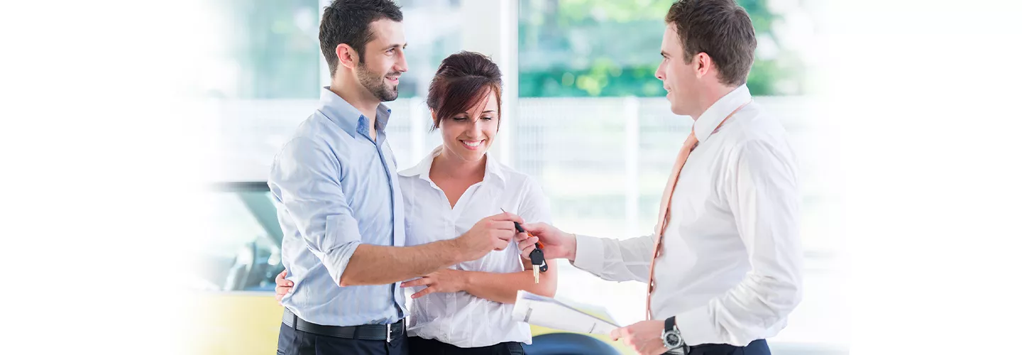Couple being handed a new set of car keys from a car salesman