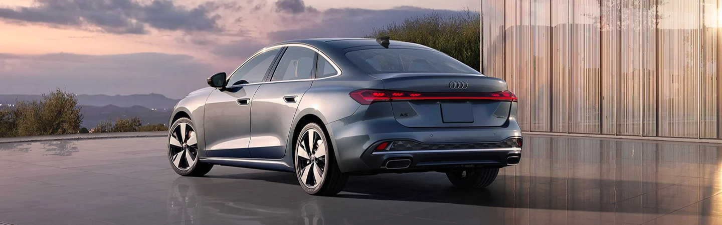 Back view of a parked 2025 Audi A5 by a house