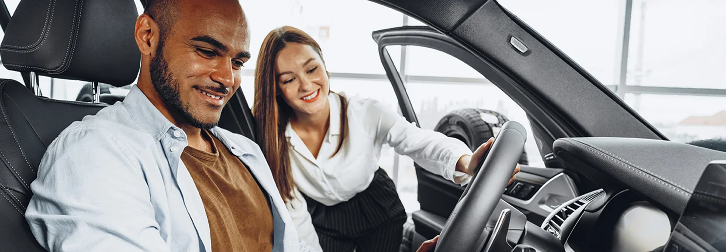 a person showing another sitting in car the features of the car