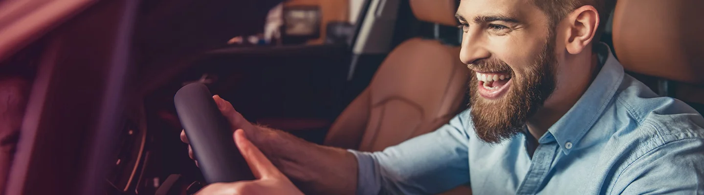 driver of a car with a hugh smile behind wheel of his new car