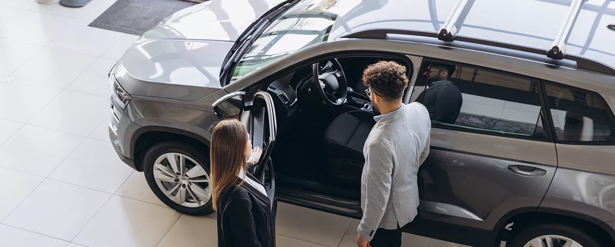 Car saleswoman showing a customer a new vehicle